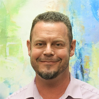 Functional Capacity Evaluator Dan Ward Smiling In Front Of Watercolor Painting