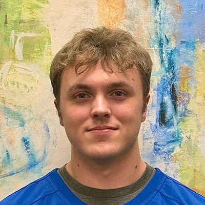 Licensed Massage Therapist Keith Huskins Smiling In Front Of Watercolor Painting