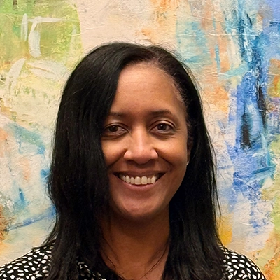 Practice Manager & Exercise Physiologist Vanessa Moar Smiling In Front Of Watercolor Painting