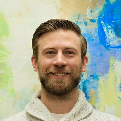 Chiropractor Scott Oliphant Smiling In Front Of Watercolor Painting