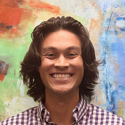 Chiropractor Zach Bird Smiling In Front Of Watercolor Painting